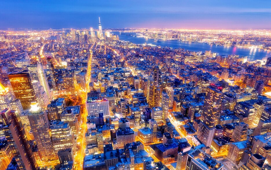 Das Bild aus der Luft zeigt den Blick auf, einen Stadtteil von New York. Zu sehen sind viele künstliche Lichtquellen in und auf den Häusern und die erleuchteten Straßenschluchten, die die Dunkelheit erhellen. Das Bild soll verdeutlichen, wie stark Kunstlicht den Tag-und-Nacht-Rhythmus von Mensch und Natur stört. Link zum Artikel.