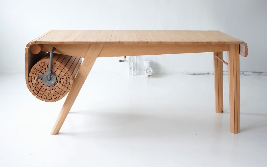 Zu sehen ist ein ausrollbarer Holztisch, der mithilfe einer Kurbel auf bis zu 4 Metern ausgerollt werden kann. Die Tischplatte entfaltet sich dabei wie eine Markise. Link zum Artikel.