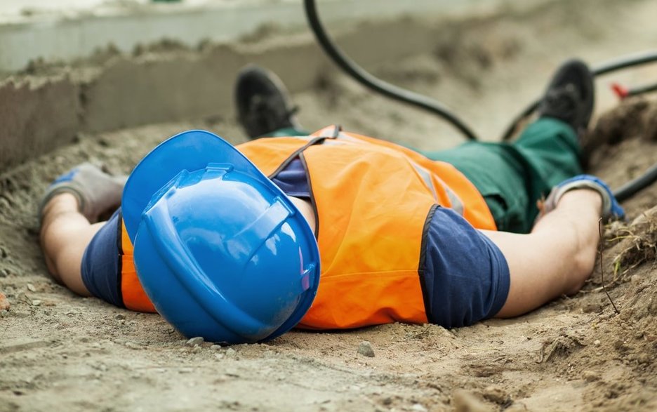 Zu sehen ist ein bewusstloser Mitarbeiter, der nach einem Stromunfall auf der Erde liegt. Dies ist ein Symbolbild für das Thema „Erste Hilfe beim Stromunfall“. Link zum Artikel.