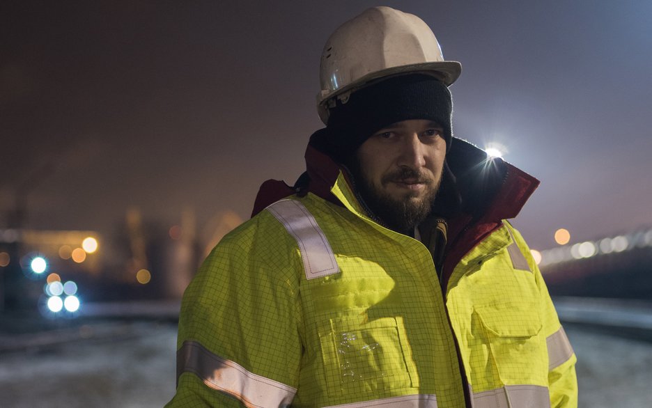 Zu sehen ist ein Arbeiter bei Nacht in Winterschutzkleidung und mit Mütze unter dem Helm. Link zum Artikel.