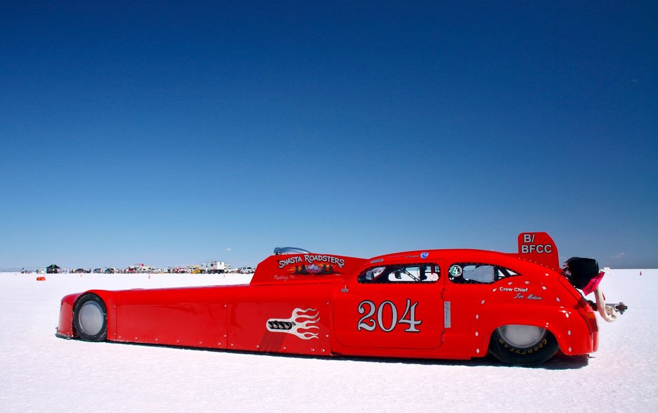 Das Bild zeigt ein extrem langes, rotes Rennauto mit sehr speziellem Design. Solche Fahrzeuge werden extra gebaut für Hochgeschwindigkeitsfahrten in der Salzwüste im Westen der USA.  Link zum Artikel.