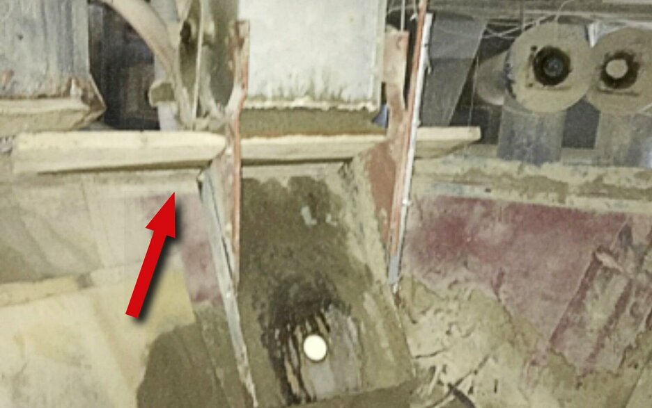 Das Bild zeigt den Blick in den Wiegebehälter eines Sandsilos. Hier ist ein Brett zu sehen, dass querliegend als Sicherung vor dem nachfließenden Sand dient. Link zur vergrößerten Darstellung des Bildes.