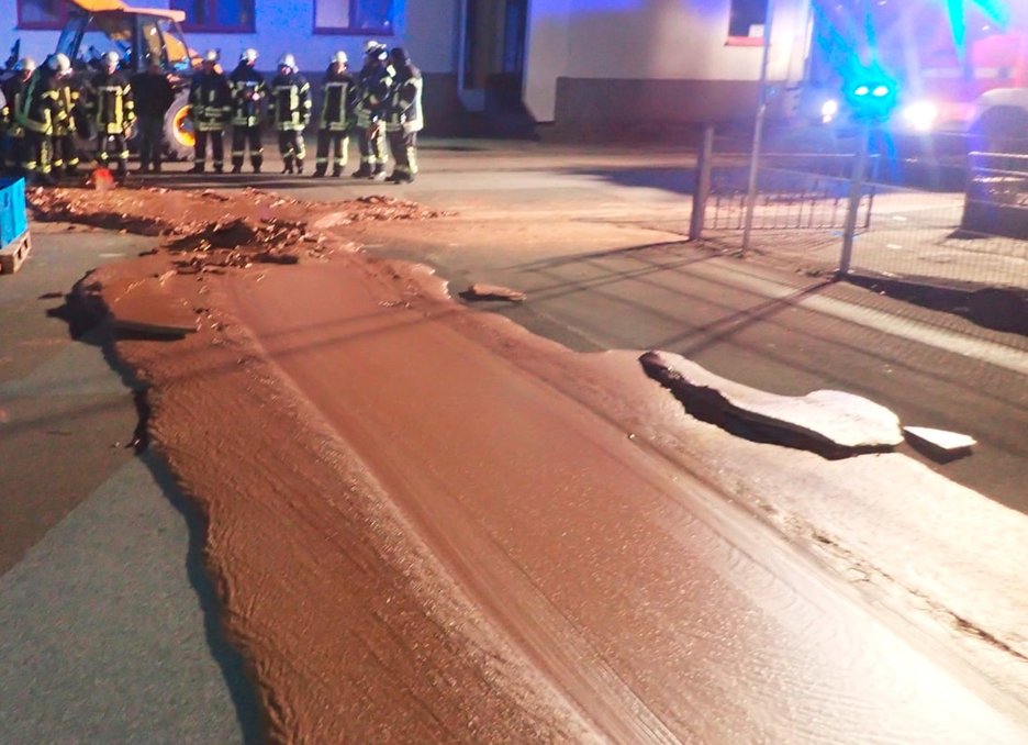 Zu sehen ist eine Straße voll von Schokolade. Die flüssige Masse war nach einem Leck im Tank eines Pralinenherstellers aus dem Gebäude auf die Straße gelaufen. Link zur vergrößerten Darstellung des Bildes.