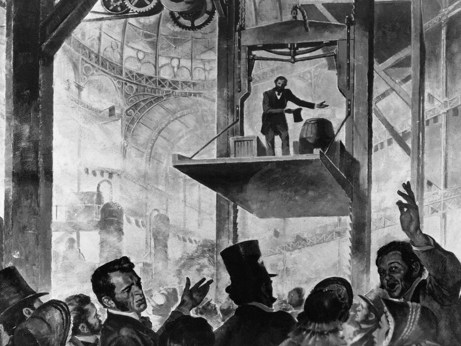 Das Schwarz-Weiß-Bild ist eine illustrative Darstellung der Weltausstellung 1854. Im Vordergrund auf der unteren Seite des Bildes ist eine Menschenmenge zu sehen, die sich aufgeregt und erstaunt miteinander unterhält. Über ihnen im Hintergrund ist ein großes Holzgestell zu sehen. Zwischen 2 vertikalen Schienen mit vielen Zähnen auf der Innenseite schwebt eine Plattform. Auf dieser stehen Kisten, Fässer und der Erfinder Elisha Graves Otis, der seinen Zylinder gezogen hat und sich verbeugt. Über ihm ist seine Erfindung zu sehen. Unter einem waagerechten Holzbalken befindet sich eine große Metallfeder, an deren Seiten links und rechts 2 Keile angebracht sind. Über dem Holzbalken ist ein durchgeschnittenes Seil. Link zur vergrößerten Darstellung des Bildes.