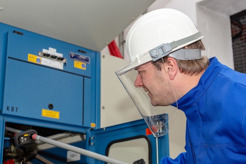 Elektrotechniker und Sicherheitsfachkraft Andreas Nienhaus arbeitet mit Persönlicher Schutzausrüstung für Elektroarbeiten in einem Schaltraum.