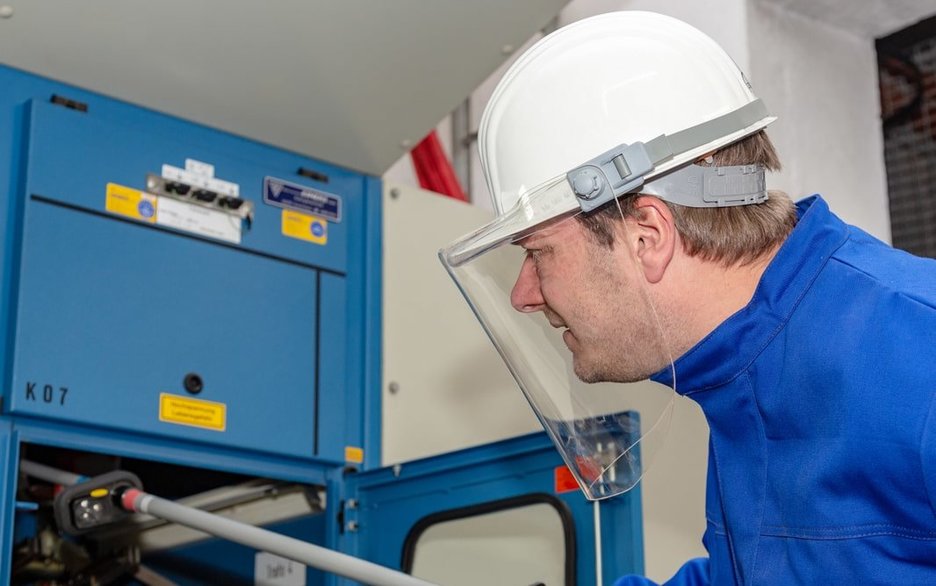 Elektrotechniker und Sicherheitsfachkraft Andreas Nienhaus arbeitet mit Persönlicher Schutzausrüstung für Elektroarbeiten in einem Schaltraum. Link zum Artikel.