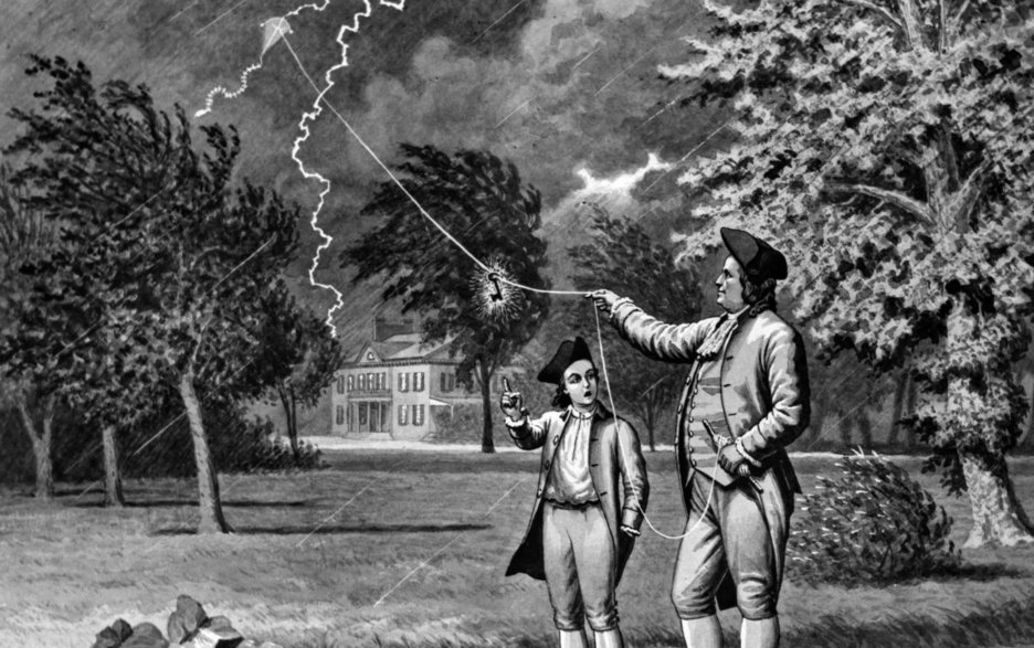 Das Bild zeigt eine schwarz-weiß Zeichnung. Zu sehen ist der Erfinder des Blitzableiters Benjamin Franklin, der dazu ein Experiment mit einem selbstgebauten Drachen durchführte. Neben ihm steht ein Kind. Link zum Artikel.