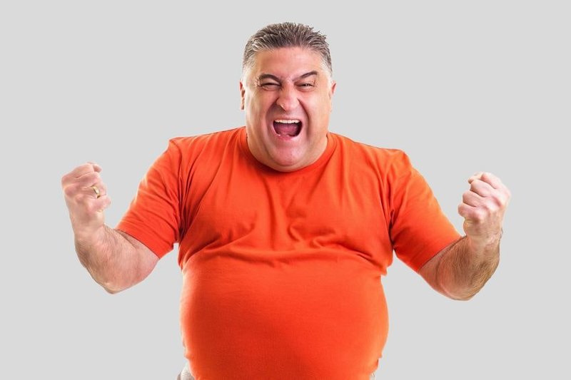 Zu sehen ist ein kräftiger Mann im orangefarbenem T-Shirt, der seine Fäuste ballt und kraftvoll schreit. Dies Symbolfoto für den Selbst-Check Zufriedenheit im Job soll die Kraft verdeutlichen, die entsteht, wenn alles super läuft im Job.