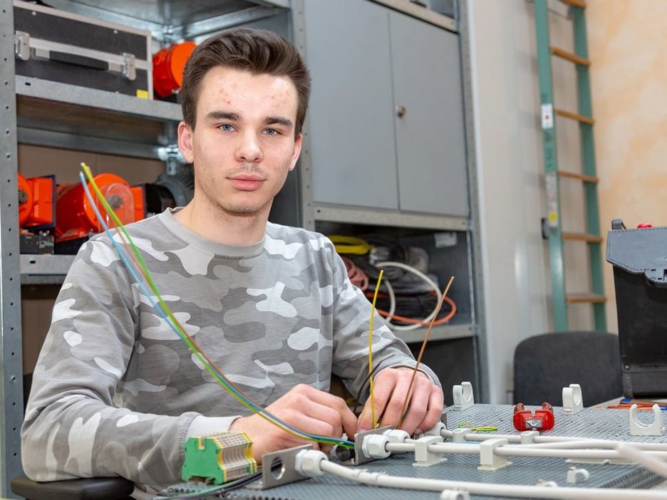 Der Auszubildende zum Energieelektroniker Luca Naß übt in der Lehrwerkstatt den sicheren Aufbau und Umgang mit Schaltkreisen. Link zur vergrößerten Darstellung des Bildes.