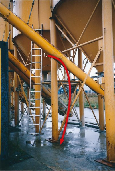 Zu sehen ist ein Silo, an dem eine lange Leiter lehnt. Ein roter Pfeil deutet an, aus welcher Höhe ein Mitarbeiter bei Klopfarbeiten von der Leiter stürzte.