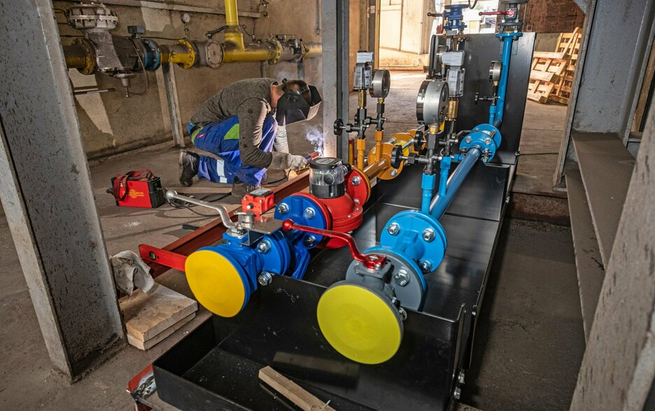 Das Foto zeigt einen Schweißer bei Instandhaltungsarbeiten an bunten Rohren im Werk Schladen der Nordzucker AG. Er trägt Persönliche Schutzausrüstung.