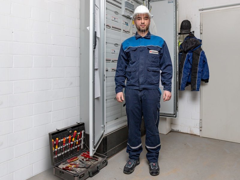 Elektroniker Eduard Partus trägt Persönliche Schutzausrüstung für Elektroarbeiten. Besonders wichtig sind ihm die antistatischen Sicherheitsschuhe, die bequem sein müssen, weil sie die ganze Zeit getragen werden.