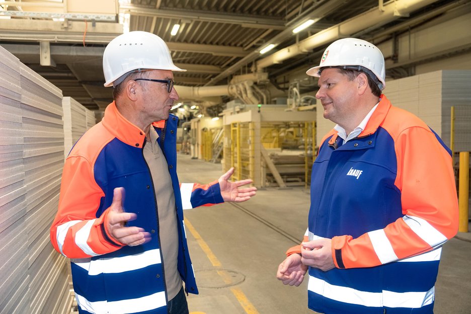 Das Bild zeigt den Werksleiter Thomas Kroiher und die Sicherheitsfachkraft Manfred Kaiser im Gespräch vor Ort in der Produktionshalle von Knauf Intergral Satteldorf.