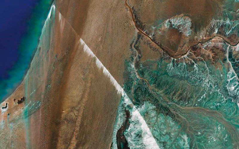 Zu sehen ist ein Satellitenbild des längsten Förderbandes der Welt. Es befindet sich in der Westsahara und transportiert Phosphat. Dies ist auch aus großer Höhe als weiße Streifen zu erkennen ist. Link zum Artikel.