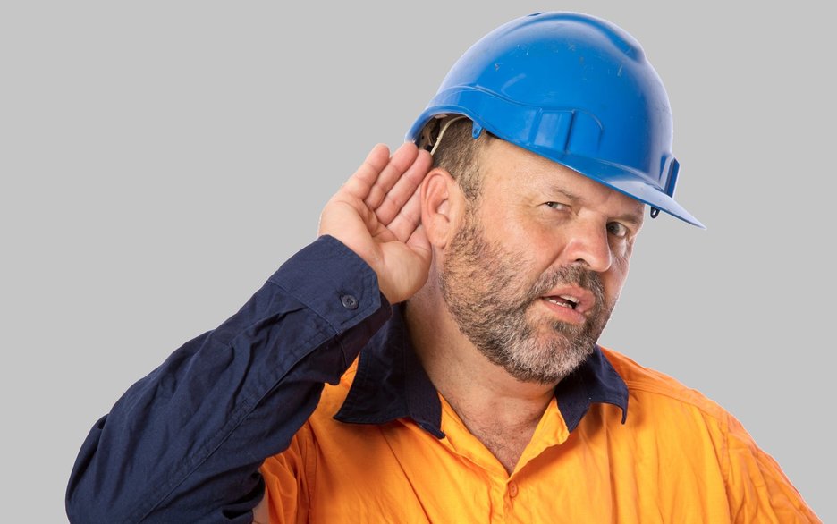 Das Bild zeigt einen Mitarbeiter, der seine Hand ans Ohr hält, um besser hören zu können. Link zur vergrößerten Darstellung des Bildes.