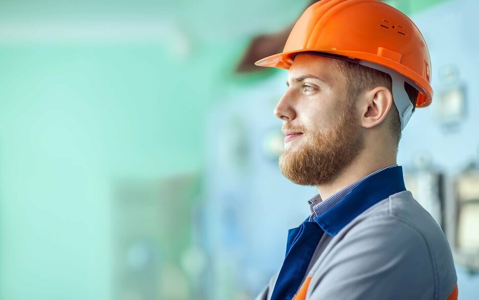 Zu sehen ist das Symbolbild eines nachdenklichen Mitarbeiters in Arbeitskleidung und mit orangefarbenem Helm. Er steht für das Thema „Arbeiten mit Diabetes“. Link zum Artikel.