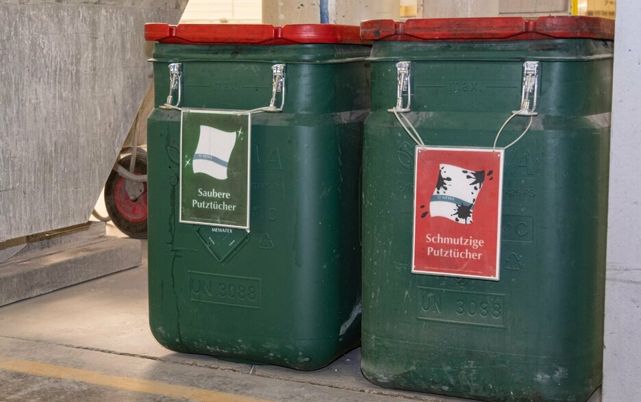 Das Bild zeigt zwei robuste Kunststoffbehälter, in denen saubere und schmutzige Putztücher separat gesammelt werden. 