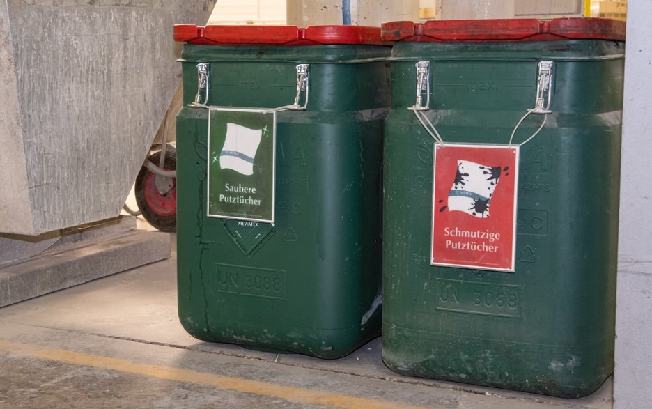 Das Bild zeigt zwei robuste Kunststoffbehälter, in denen saubere und schmutzige Putztücher separat gesammelt werden.