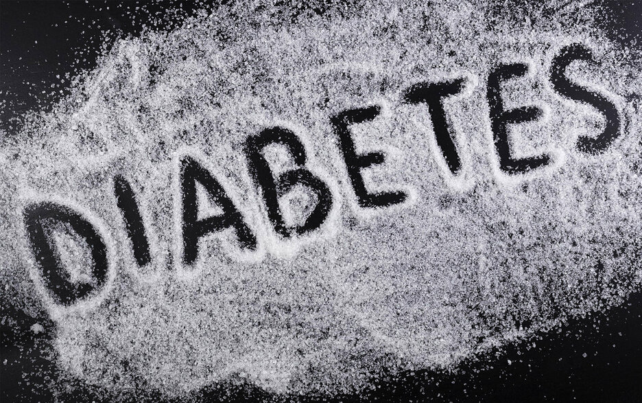 Zu sehen ist eine mit weißem Zucker bestreute schwarze Oberfläche, in die jemand das Wort „Diabetes“ mit dem Finger geschrieben hat. Link zum Artikel.