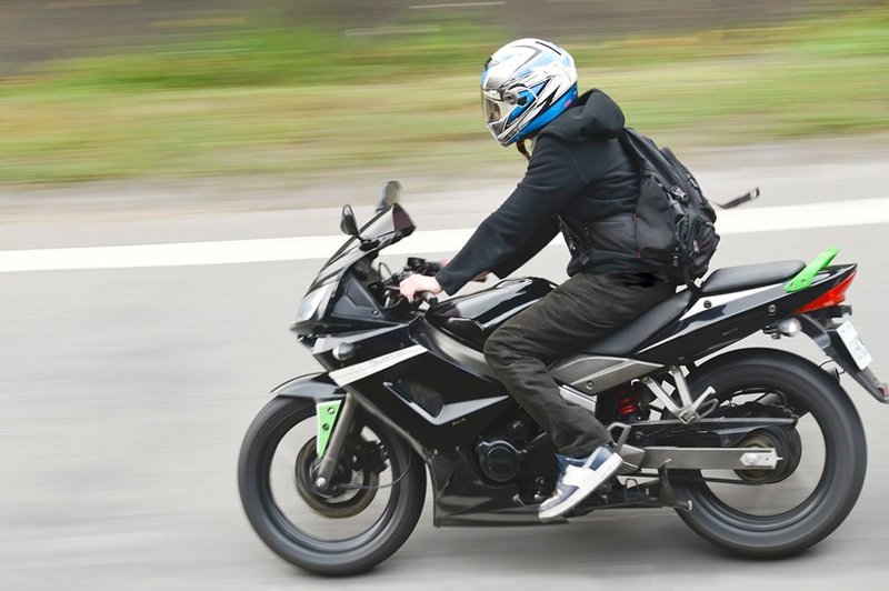 Zu sehen ist ein Motorradfahrer mit Helm während der schnellen Fahrt.