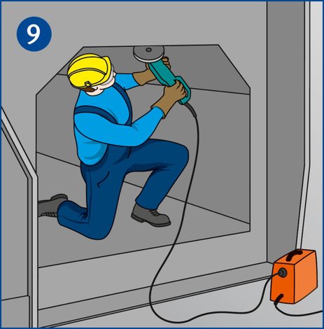 Ein Mitarbeiter arbeitet in einem engen, metallischen Raum mit einer elektrischen Handmaschine. Hierbei handelt es sich um Arbeiten unter erhöhter elektrischer Gefährdung.