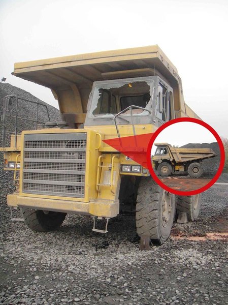 Das Bild zeigt einen beschädigten Schwerkraftwagen, mit dem ein alkoholisierter Mitarbeiter beim Abladen von Schotter über die Kippkante stürzte. In einer eingeklinkten Lupe sieht man das Fahrzeug von der Seite an der Kippkante.