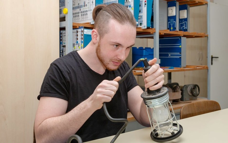 Der Auszubildende zum Chemikanten Joshua Engel macht eine Sicht- und Funktionskontrolle am Kabel einer Elektrolampe. Link zum Artikel.