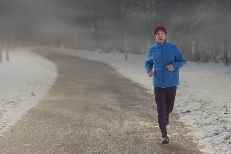 Zu sehen ist ein joggender Mann im Winter, hinter dem schwarze Wolken eine düstere Stimmung verbreiten. Dies steht als Symbol für das Thema „Winterdepressionen“.
