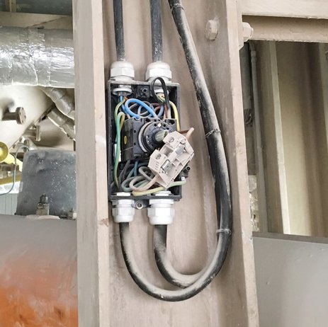 Das Bild zeigt freiliegende Elektrokabel an einer Anlage. Hier können Mitarbeiter schnell mit dem Körper an gefährliche Spannung geraten.