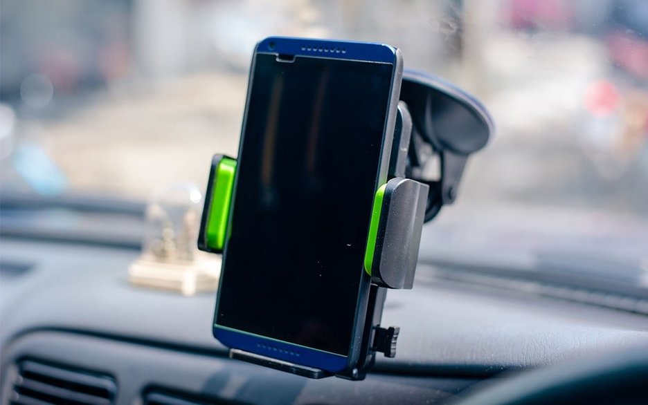 Zu sehen ist ein Smartphone, das im Auto fest in einer Halterung sitzt.