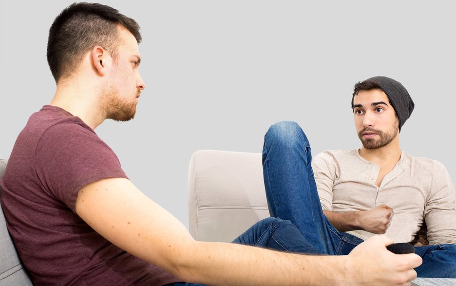 Zwei junge Kollegen sitzen entspannt zusammen und reden ernsthaft miteinander. Dieses Symbolbild zeigt, wie wichtig das ehrliche Gespräch beim Thema Sucht im Betrieb ist.  Link zum Artikel.
