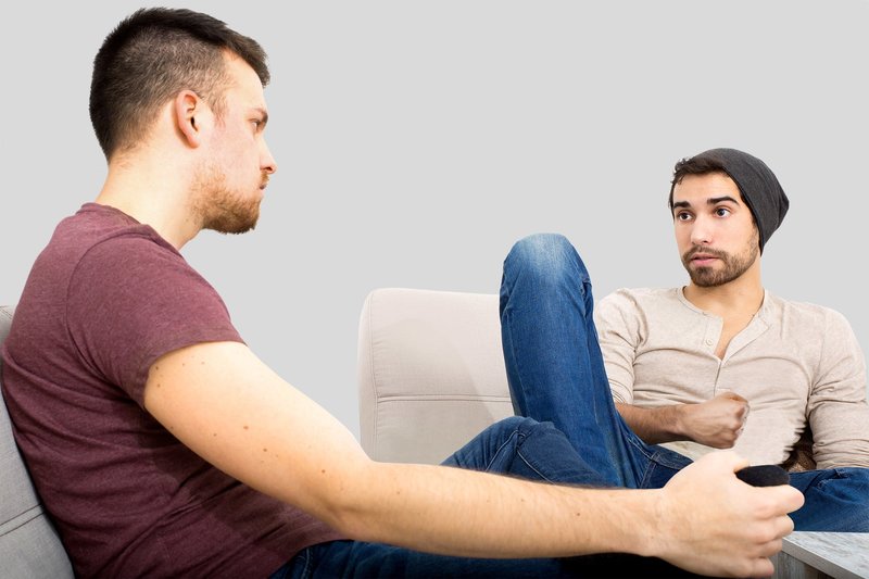 Zwei junge Kollegen sitzen entspannt zusammen und reden ernsthaft miteinander. Dieses Symbolbild zeigt, wie wichtig das ehrliche Gespräch beim Thema Sucht im Betrieb ist. 