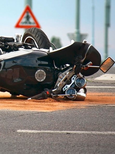 Zu sehen ist ein verunfalltes Motorrad, das auf der Seite liegt mit Ölbindemittel drumherum auf der Straße.
