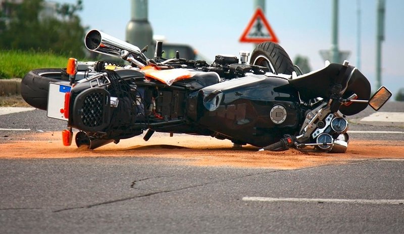 Zu sehen ist ein verunfalltes Motorrad, das auf der Seite liegt mit Ölbindemittel drumherum auf der Straße.