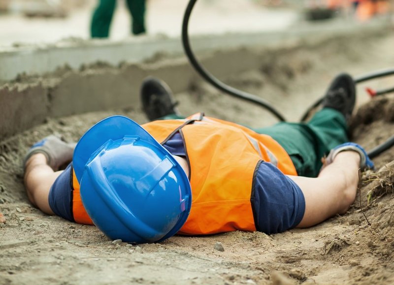 Zu sehen ist ein bewusstloser Mitarbeiter, der nach einem Stromunfall auf der Erde liegt. Dies ist ein Symbolbild für das Thema „Erste Hilfe beim Stromunfall“.