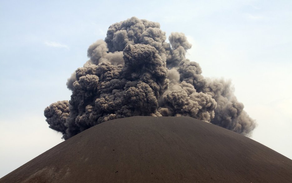 Das Bild zeigt einen Vulkanausbruch mit explosionsartig herausschießenden schwarz-grauen Aschewolken.