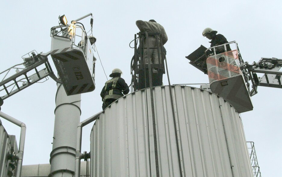 Das Bild zeigt Höhenretter der Feuerwehr, die von Drehleitern aus zwei verunfallte Mitarbeiter von oben aus dem Silo bergen.  Link zum Artikel.