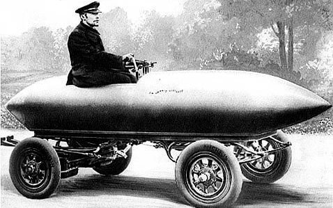 Zu sehen ist ein alter Schwarz-Weiß-Stich mit dem Rennfahrer und Konstrukteur Camille Jenatzky in seinem Rekordelektroauto aus dem 19. Jahrhundert..