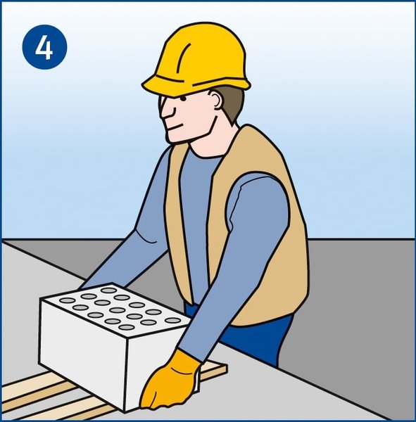 Ein Mitarbeiter, der Schutzhandschuhe trägt, setzt einen schweren Stein auf eine geeignete Unterlage, um seine Hände nicht zu quetschen.
