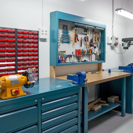Das Bild zeigt eine Werkzeugbank, an der Maschinen und Werkzeuge geprüft, gereinigt und sicher gelagert werden.