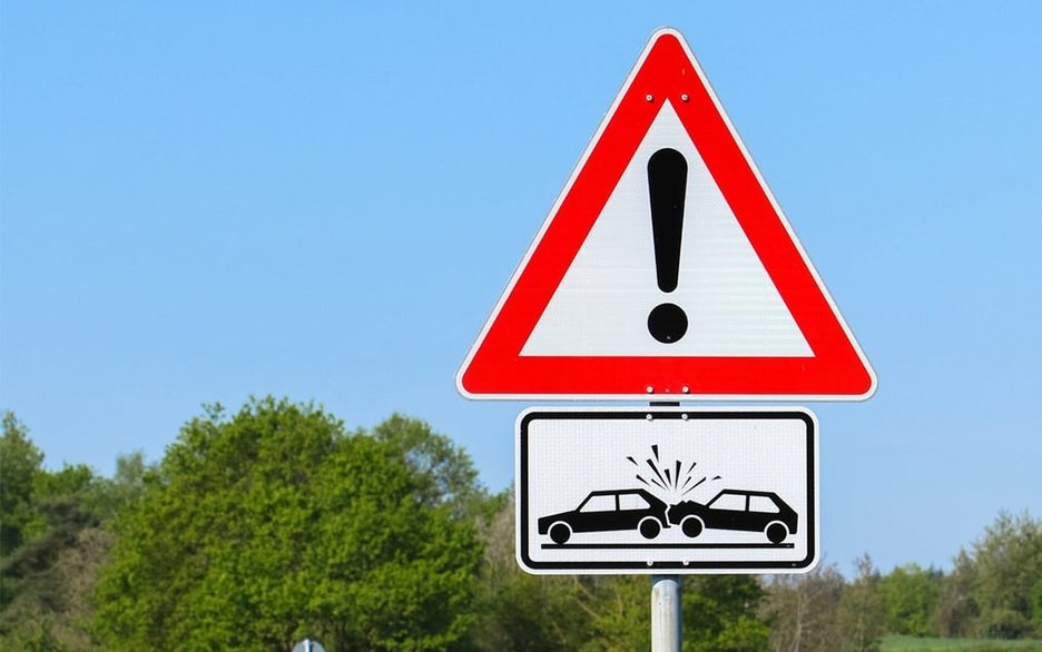 Ein Verkehrsschild auf einer kurvigen Landstraße warnt vor Auffahrunfällen an einer Einbiegung rechts und links.