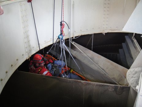 Das Bild zeigt die Durchführung einer Rettungsübung in einem Mischerturm. Der angenommen Verunfallte wird zusammen mit dem Höhenretter auf einer angeseilten Rettungstrage aus dem Silo gezogen.  Link zur vergrößerten Darstellung des Bildes.