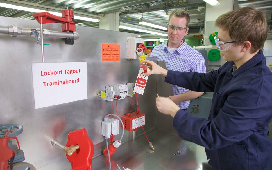 Das Bild zeigt ein Lockout-Tagout Trainingsboard. Hier übt ein Mitarbeiter die sichere Verriegelung und Kennzeichnung von Schaltern und Ventilen.  Link zum Artikel.