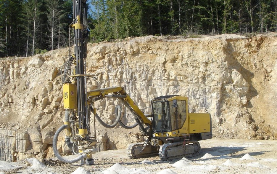 Das Bild zeigt ein Bohrgerät im Einsatz in einem Steinbruch. Dieses wollte ein Mitarbeiter zu einer oberhalb gelegenen Bohrstelle fahren.