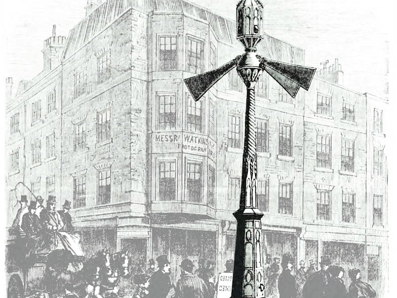 Zu sehen ist ein alter Stich in schwarz-weiß, der eine Signalanlage mit drei Armen zeigt, die von John Peake Knight erfunden wurde. Die Anlage steht an einer Londoner Kreuzung und regelt den Verkehr im 19. Jahrhundert. Bedient wurde diese von einem Beamten. Arm oben bedeutete stopp, Arm unten freie Fahrt.