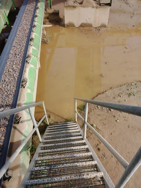 Das Bild zeigt eine Stahltreppe, die nach unten führt. Am Boden des Treppenaufgangs befindet sich eine große Wasseransammlung.