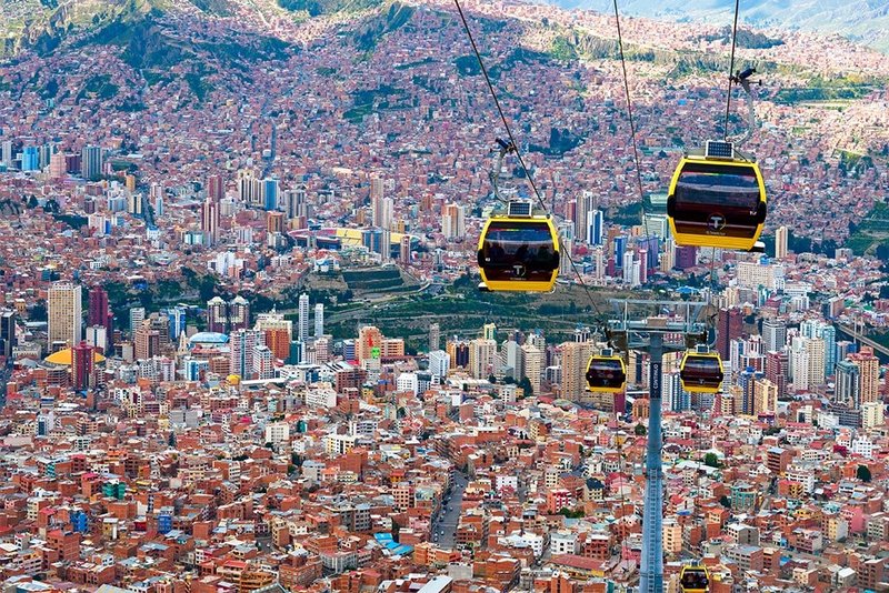 Zu sehen ist eine Seilbahn mit gelben Gondeln und abgedunkelten Scheiben für Berufspendler in Bolivien, die die Millionenstadt La Paz mit der Arbeitervorstadt El Alto verbindet.